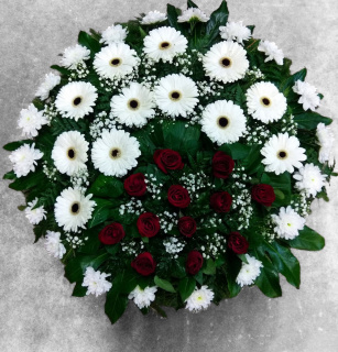 A funeral wreath with dark red roses, white gerberas, and chrysanthemums